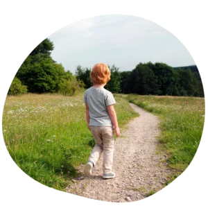 Photo d'un enfant de dos qui marche sur un chemin à la campagne.